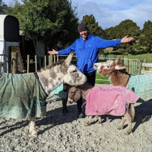 Homeowner and house sitters with donkeys on a farm, showcasing trust and care in a rural setting.